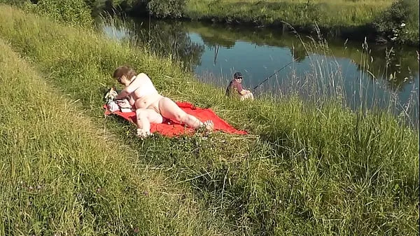 Big MILF sexy Frina on river bank undressed and sunbathes naked. Random man fisherman watching for her, and in the end decided to join naked woman. Wild beach. Nudist beach. Public nudity. Public exposure. Naked in public top Clips