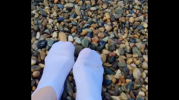 Playing with my feet in white socks with pebbles on the beach Klip teratas besar